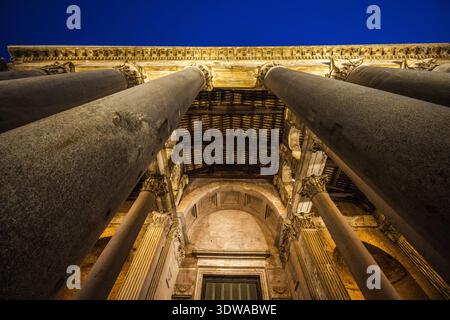 Vista dall'angolo basso dell'ingresso del Pantheon a Roma con enormi colonne antiche e dettagli architettonici illuminati di notte Foto Stock