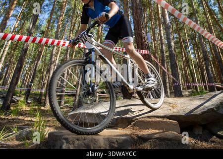 Giro in mountain bike su grandi pietre nella foresta recintata con nastro segnaletico Foto Stock