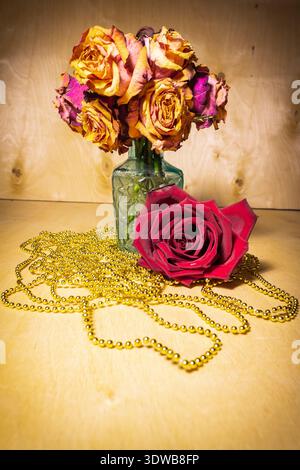 Bouquet di rose selvatiche in vaso di vetro con rose rosse fresche e perline dorate, concetto di amore e tempo che svanisce Foto Stock
