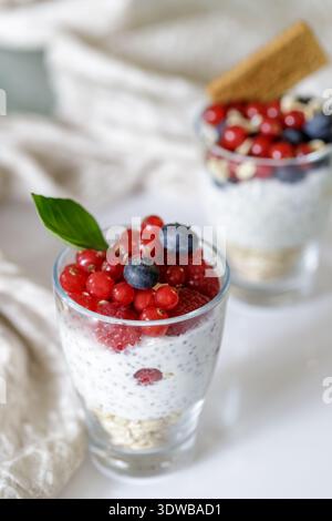 Gustoso budino di yogurt con frutti di bosco in vasetti di vetro per mangiare sano su sfondo leggero. Messa a fuoco selettiva Foto Stock