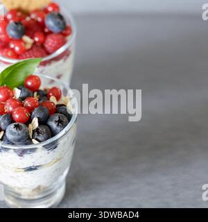 Delizioso budino di yogurt, frutti di bosco e frutta in vasetti di vetro per una sana alimentazione su sfondo chiaro. Messa a fuoco selettiva Foto Stock