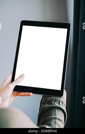 Primo piano di una persona che tiene un tablet con schermo bianco vuoto all'interno. Composizione minimale e moderna, ideale per presentazioni di app, mockup di siti Web, digitale Foto Stock