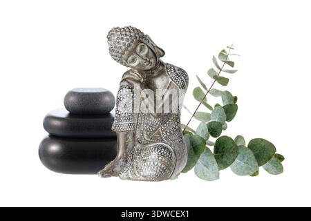 Vecchia statuetta color argento che dorme Buddha con pietre zen nere e rametti di eucalipto isolati su sfondo bianco. Meditazione o relax nel centro benessere Foto Stock