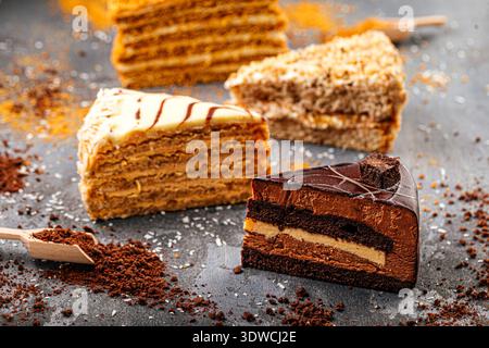 Fette di torta assortite su un tavolo scuro Foto Stock