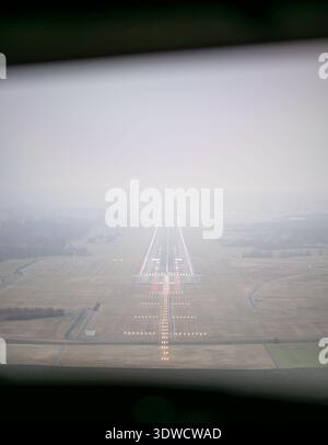 Vista della cabina di pilotaggio dell'aeroplano, con le luci della pista mentre ci si avvicina all'aeroporto con la nebbia Foto Stock