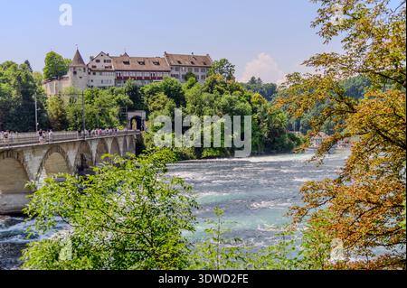 Vista panoramica delle Cascate del Reno (Rheinfall) dall'alto, con il castello Schloss Laufen sullo sfondo. Un ponte di pietra con pedoni attraversa il Foto Stock