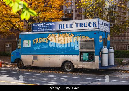 Toronto, Canada, 20 ottobre 2025: Un camion di cibo blu che serve patatine fritte e altri piatti di Street food parcheggiato lungo una strada della città durante la stagione autunnale. Foto Stock