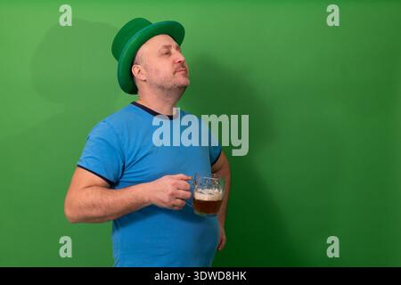 Uomo che indossa un cappello verde di leprechaun che regge una tazza di birra. Festa irlandese e divertimento per il St. Patricks Day. Tradizione natalizia con fotografia del concetto di pub Foto Stock