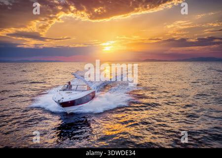 Vista frontale aerea di un motoscafo che naviga sull'oceano durante il tramonto estivo dorato con spazio per copiare Foto Stock