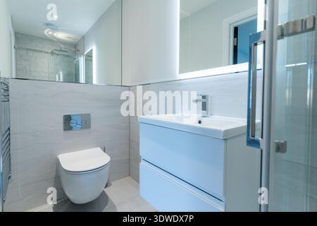 Bagno contemporaneo in una casa londinese con finiture eleganti, WC a parete, specchio illuminato e cabina doccia moderna, emblema di un'eleganza Foto Stock