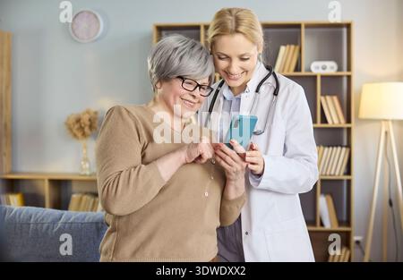 Donna anziana e medico donna che utilizza lo smartphone per la guida e il supporto online Foto Stock