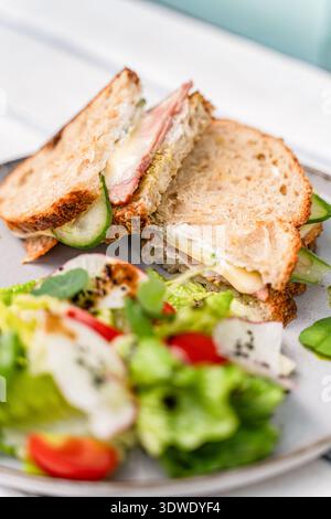 Un generoso toast con prosciutto e formaggio servito con un'insalata fresca e vivace. Pane croccante, prosciutto saporito, formaggio fuso e un mix rinfrescante di verdure Foto Stock