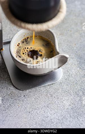 Il caffè espresso aromatico fluisce in una tazza di ceramica, creando una crema ricca e schiumosa. Il caffè appena preparato offre un momento di piacere ed è perfetto Foto Stock