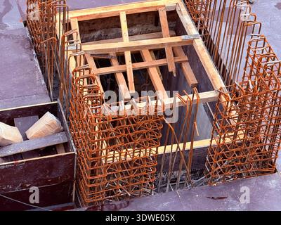 Un'immagine che mostra l'intricato processo di costruzione di travi in cemento armato, evidenziando i rinforzi per armature e i supporti in legno all'inizio del c Foto Stock