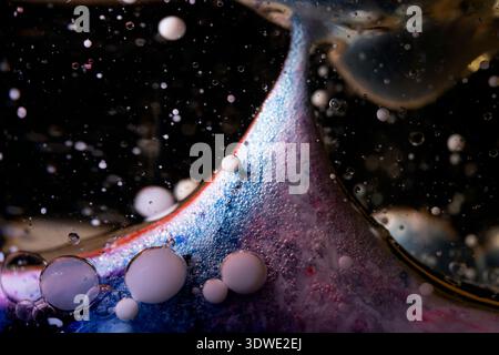 Un'immagine astratta ipnotizzante con colori vivaci che ruotano tra le bolle, creando un effetto onirico. Il movimento fluido aggiunge profondità a questo captiv Foto Stock