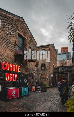 Londra, Regno Unito - 31 gennaio 2026: Veduta del vibrante bagliore al neon del cartello "Coyote Ugly" che contrasta con gli edifici in mattoni e il co Foto Stock