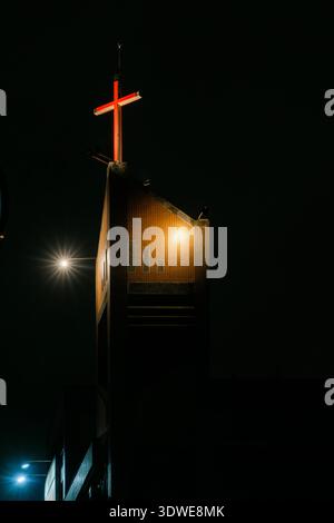 La croce rossa luminosa in cima a una chiesa moderna contrasta con il cielo notturno di Taiwan, in Asia. Foto Stock