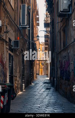 Uno stretto vicolo acciottolato incastonato tra vecchi edifici nel quartiere storico di Palermo, che mostra la vita urbana, la vivace Street art e l'affascinante E. Foto Stock