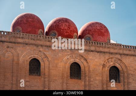 Affascinante vista dell'architettura storica di Palermo, caratterizzata da distintive cupole rosse in cima a una facciata in pietra. Gli intricati archi riflettono il ric della città Foto Stock