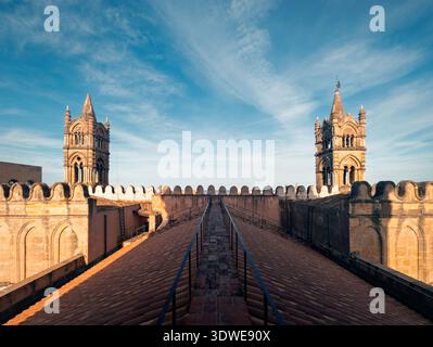 Splendida prospettiva sul tetto della storica cattedrale di Palermo, che mostra intricati dettagli architettonici delle sue torri gemelle sotto un blu vibrante Foto Stock
