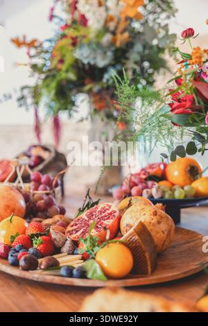 Un piatto rustico in legno ripieno di una varietà di frutta fresca, tra cui fragole, mirtilli, uva, melograni, fichi e cachi, concomp Foto Stock