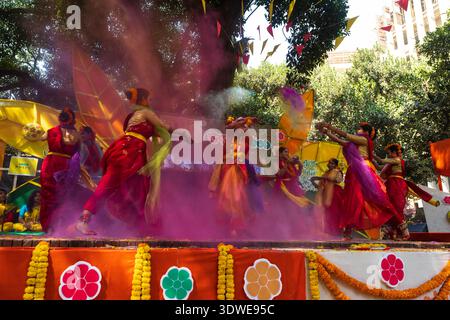Dhaka, Bangladesh - 4 marzo 2018: Veduta dei ballerini in vibranti costumi rossi e gialli si esibiscono in mezzo a una nuvola di polvere di Holi rosa, celebrando un colorante Foto Stock