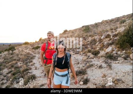 Una giovane coppia fa un'escursione attraverso un panoramico Red Canyon in Spagna, abbracciando la natura e l'avventura. Navigano su sentieri rocciosi, mostrando la bellezza della lan Foto Stock