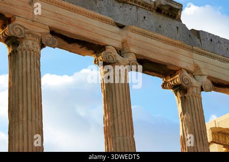 Vista ravvicinata delle antiche colonne dell'Eretteo ad Atene, in Grecia. L'architettura iconica si erge su di un cielo blu brillante, riflettendo la sua altezza Foto Stock