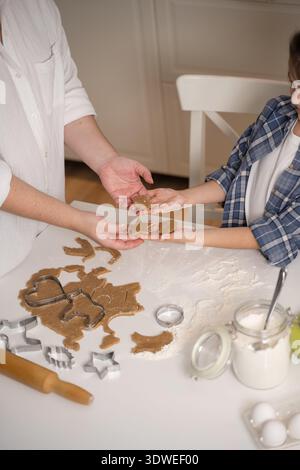 Una madre e una figlia si divertono a cucinare biscotti insieme a casa. Condividono uno speciale momento di incollaggio, passando l'impasto tra i due Foto Stock