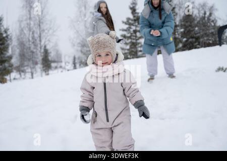 Un momento di gioia catturato come madre e bambini si godono un divertente momento invernale nel parco. Vestiti con calore, abbracciano il paesaggio innevato con smi Foto Stock