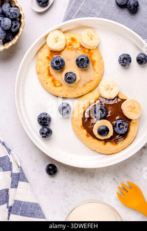 Una deliziosa colazione con soffici pancake conditi con mirtilli freschi e fette di banana. Ideale per un nutriente pasto mattutino o una bruna dolce Foto Stock