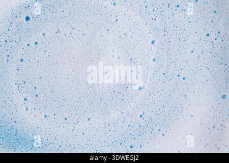 Vista ravvicinata della delicata schiuma blu matcha su sfondo chiaro, che mostra un'ipnotica sequenza di bolle. La texture sottile crea un effetto rilassante Foto Stock