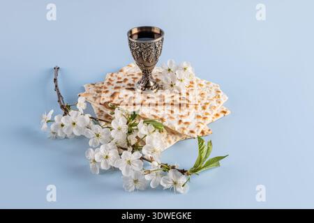 Un allestimento cerimoniale per Pesach caratterizzato da matzah tradizionale, un calice di vino d'argento e fiori bianchi in fiore, che rappresentano un significativo centro ebraico Foto Stock