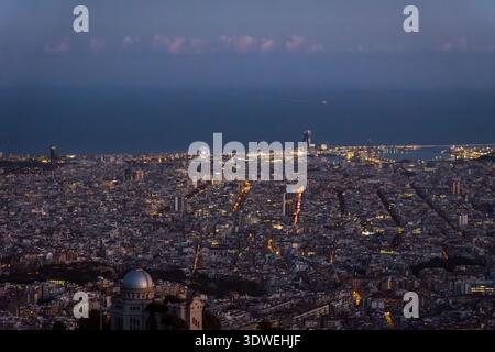 Una splendida vista di Barcellona dal Tibidabo al crepuscolo, che mostra il vasto paesaggio urbano sotto una luna in ascesa. Le luci luminose della città creano un mesmeri Foto Stock