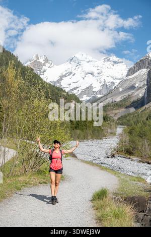 Un escursionista apprezza il paesaggio primaverile mozzafiato vicino al lago Oeschinen nelle Alpi svizzere. Il paesaggio è caratterizzato da montagne innevate, foreste lussureggianti e un Foto Stock
