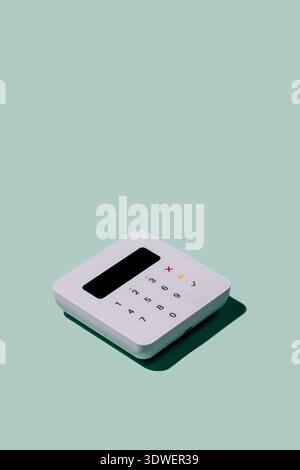 Terminale POS compatto con tastierino numerico e display su uno sfondo verde menta. Ideale per aziende moderne che cercano un pagamento elegante ed efficiente Foto Stock