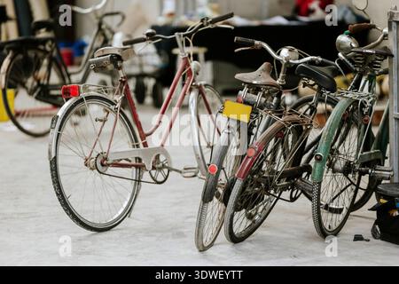 Un gruppo di biciclette d'epoca con sedili indossati e telai arrugginiti sono parcheggiate vicino all'interno. Le moto hanno un'estetica retrò che mostra la loro Foto Stock