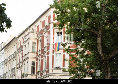 Berlino, Germania - 19 agosto 2025: L'architettura storica presenta una bandiera arcobaleno esposta da una finestra in città. Foto Stock