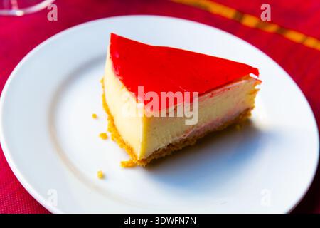 Fetta di dolce cheesecake con strato di gelatina di fragole Foto Stock