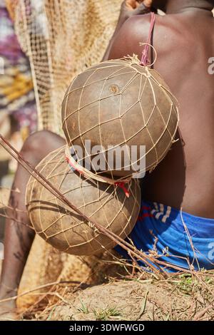 Argungu, Nigeria - 14 febbraio 2026: Veduta di un uomo con pelle scura che tiene in mano i buongustai della pesca avvolti in reti, una scena rustica piena di toni terrosi A. Foto Stock