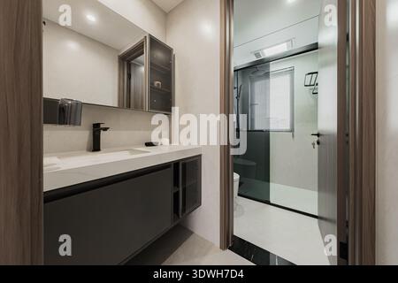 Il bagno dal design pulito dispone di lavandino, specchio e area doccia. Questo spazio mette in risalto arredi moderni e arredi semplici per un layou funzionale Foto Stock