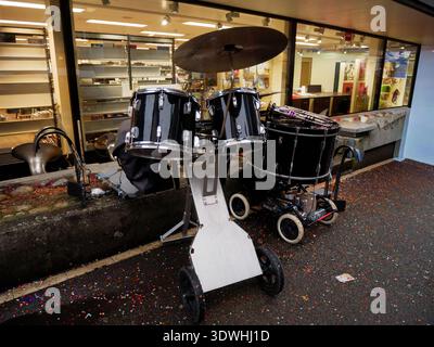 Kit tamburo nero con piatti su un supporto a ruote collocato all'esterno di un edificio con coriandoli sparsi Foto Stock