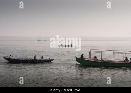 Diverse barche con persone sul fiume Gange a Varanasi, in India, sotto un cielo nebbioso. Foto Stock