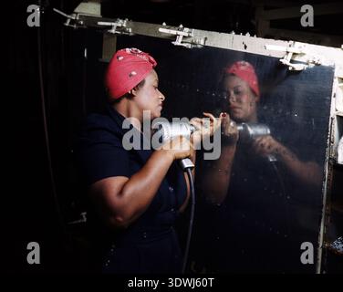 Questa potente fotografia del 1943 di Alfred T. Palmer cattura una donna afroamericana che lavora come "Rosie the Riveter" con un trapano a mano a Vultee-Nashville in Tennessee. È diligentemente coinvolta nella produzione di un bombardiere in picchiata A-31 Vengeance, simboleggiando il ruolo vitale svolto dalle donne nello sforzo bellico durante la seconda guerra mondiale Foto Stock