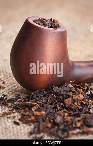 Macro di tubo di fumo e tabacco sulla tela di lino sfondo Foto Stock