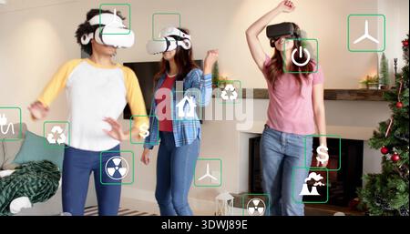 Tre donne in piedi che indossano abiti casual utilizzando icone AR galleggianti in salotto, cuffie VR Foto Stock