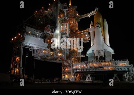 Lo Space Shuttle Discovery è illuminato di notte presso la rampa di lancio prima della missione STS-114 verso la stazione spaziale Internazionale, probabilmente nel 2005. Questa potente scena cattura la complessa struttura della torre di lancio e la prontezza dello shuttle per il suo viaggio nello spazio, mostrando ingegno umano ed esplorazione. Foto Stock