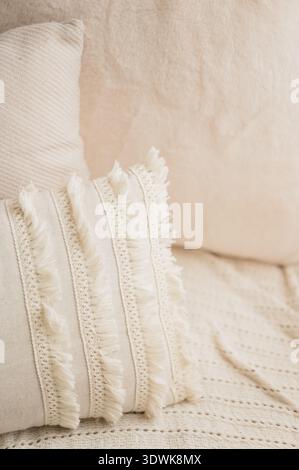 Primo piano di cuscini con frange color crema su un comodo divano neutro Foto Stock