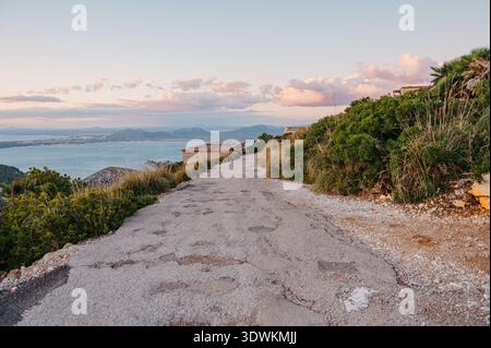 Strada costiera che conduce verso il mare al tramonto a Maiorca, Spagna Foto Stock