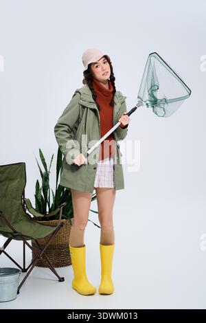 Un giovane pescatore si trova in uno studio, pronto a pescare con la sua attrezzatura. Foto Stock